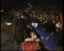 a man playing a guitar with a shirt that says " fuck alive " on it