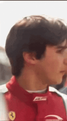 a close up of a man 's face wearing a red vest with a ferrari logo on it .
