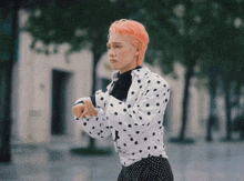 a woman with pink hair wearing a polka dot shirt