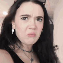 a woman wearing a choker and earrings with keys on them makes a funny face