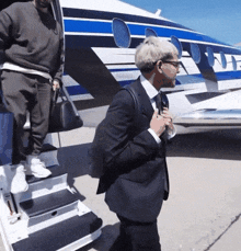 a man in a suit is walking up the stairs of a plane