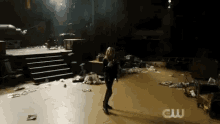 a woman is standing in a dark room with a lot of trash on the floor and stairs .