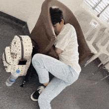 a man is sleeping on the floor next to a mcm backpack