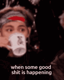 a person is drinking a cup of coffee while wearing a headband .
