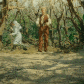 a man and a woman are standing in a lush green forest