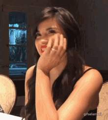 a woman with a ring on her finger is sitting at a table with her hand on her face