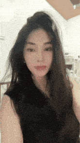 a woman with long hair is wearing a black tank top and making a funny face .