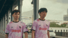 two young men wearing pink shirts with orange on them