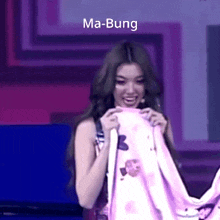 a woman is holding a pink blanket and smiling with the words ma-bung above her