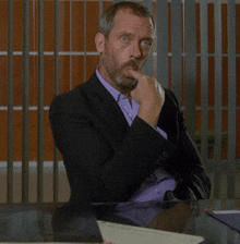 a man in a suit sits at a table with a laptop