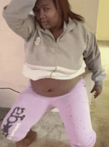 a woman wearing a grey jacket and pink sweatpants with the letter e on the bottom