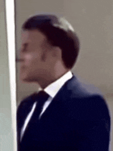 a man in a suit and tie is standing in front of a window .