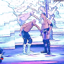 two wrestlers shaking hands on a stage with a watermark that says ' thenextbigthing '
