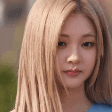 a close up of a woman 's face with blonde hair and a blue shirt .