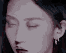 a close up of a woman 's face with her eyes closed and earring .