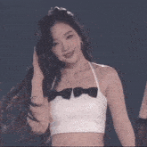 a group of women are dancing on a stage and one of them is wearing a white top and black skirt