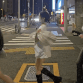a woman in a white dress is walking across a street at night