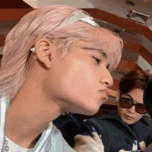 a close up of a person 's face with pink hair and sunglasses on .