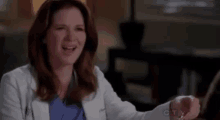 a woman in a lab coat and scrubs is talking to another woman .