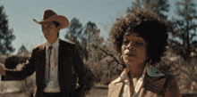 a man in a cowboy hat stands next to a woman in a suit