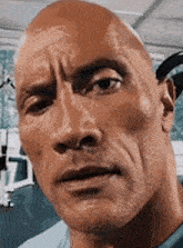 a close up of a bald man 's face with a serious expression .