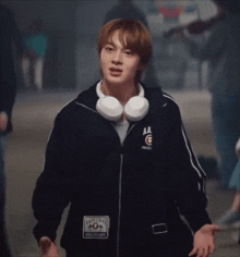a young man wearing headphones and a black jacket with the letter aa on it