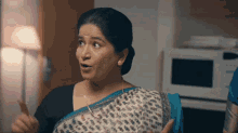 a woman in a blue and white striped saree is making a funny face