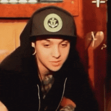 a young man wearing a hat with an anchor on it .