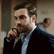 a man with a beard talks on a cell phone