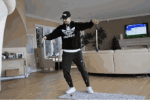 a man wearing a black adidas hoodie is dancing