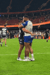 two rugby players hugging each other on a field .