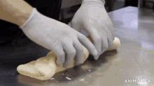 a person wearing gloves is rolling dough on a table .