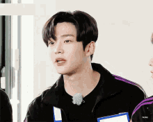 a young man wearing a black jacket with purple stripes and a name tag that says bryday