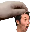 a hand is holding a man 's head in front of a white background .