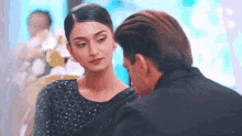 a man and woman are looking at each other and the woman is wearing a black saree