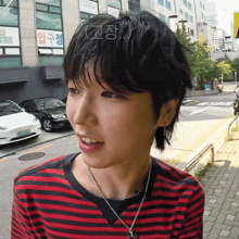 a woman wearing a red and black striped shirt is standing on a street