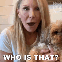 a woman holding a small dog with the words who is that behind her