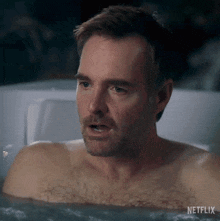 a shirtless man is taking a bath in a jacuzzi .