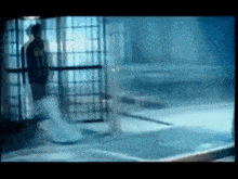 a man is walking out of a jail cell in a dark room .