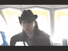 a man wearing a cowboy hat is sitting in a bus