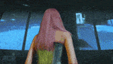 a woman with pink hair is standing in front of a computer screen
