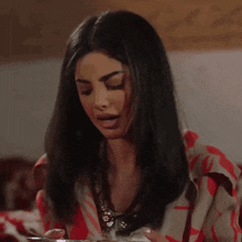 a woman is sitting at a table with a bowl of food in her hand .