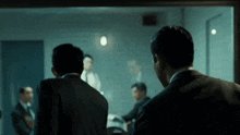 a group of men in suits are having a meeting in a dark room