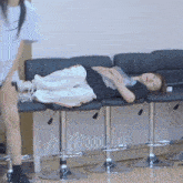 a woman laying on a row of chairs with her legs crossed
