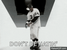 a man in a baseball uniform is standing in a tunnel and holding a bottle of water .