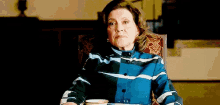 an elderly woman is sitting in a chair with a cup of coffee .