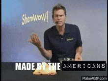 a man in a blue shirt says " shamwow " in front of a sign that says " made by the americans "