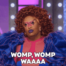 a drag queen says womp womp waaaa in a pink and blue dress
