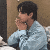 a man sitting at a table with his hands folded