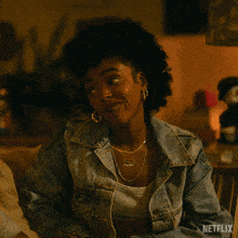 a woman in a denim jacket is sitting on a couch with netflix written on the bottom right